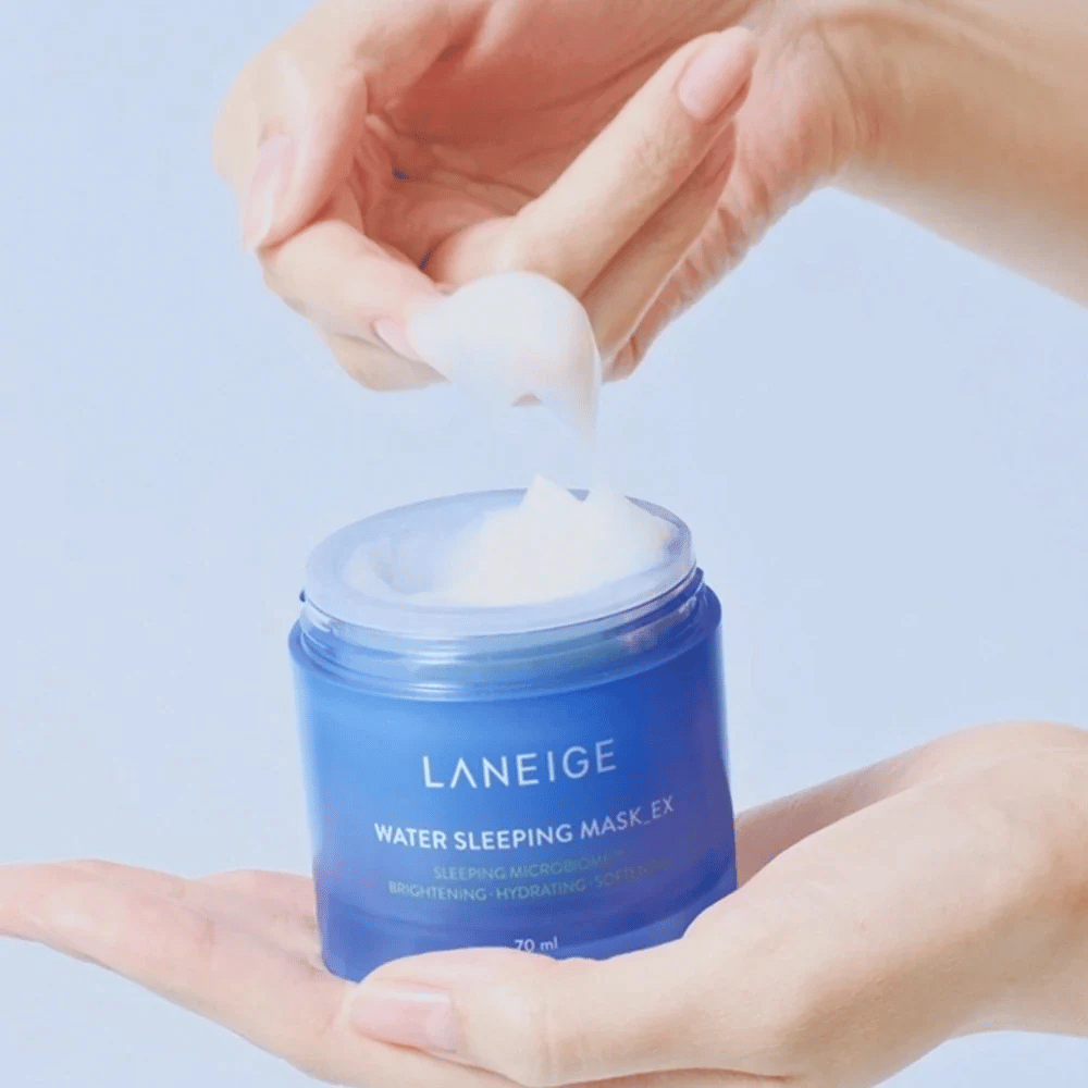 En hand skopar upp LANEIGE Water Sleeping Mask från en blå burk, med fokus på den geléliknande konsistensen mot ljusblå bakgrund.