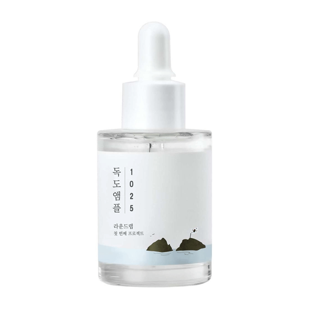 Ένα διάφανο μπουκάλι με ορό προσώπου 1025 Dokdo Ampoule, διακοσμημένο με μινιμαλιστικό θαλάσσιο θέμα, σε λευκό φόντο.