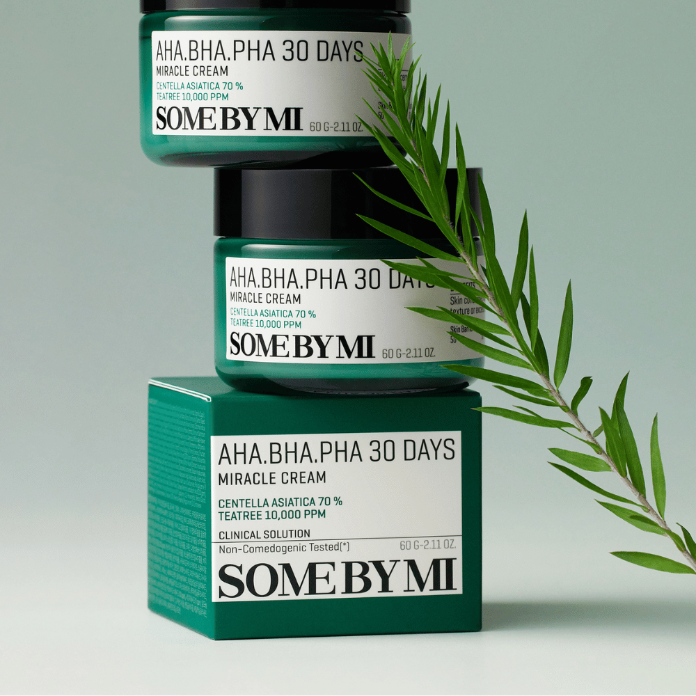 Μια εικόνα που δείχνει δύο βάζα από "SOME BY MI AHA, BHA, PHA 30 Days Miracle Cream" στοιβαγμένα σε ένα πράσινο τονισμένο κουτί. Η κρέμα, που είναι πλούσια σε centella asiatica και tea tree-έλαιο, είναι σχεδιασμένη για να βελτιώνει την ποιότητα του δέρματος και να ανακουφίζει προβληματικές επιδερμίδες. Δρα ενυδατικά και καταπραϋντικά.