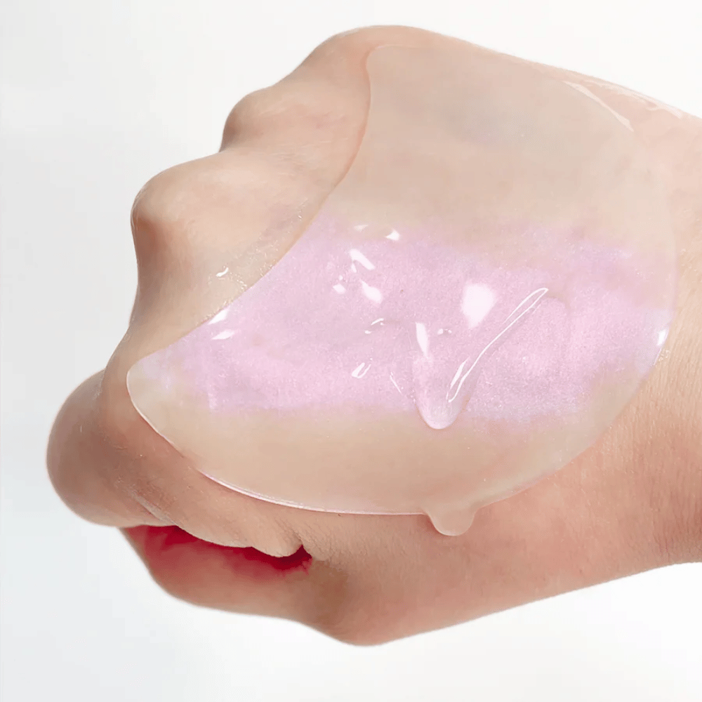 Ροζ hydrogel eye patch με ρετινόλη εμφανίζεται σε ένα χέρι, ενυδατική και λαμπερή φόρμουλα.