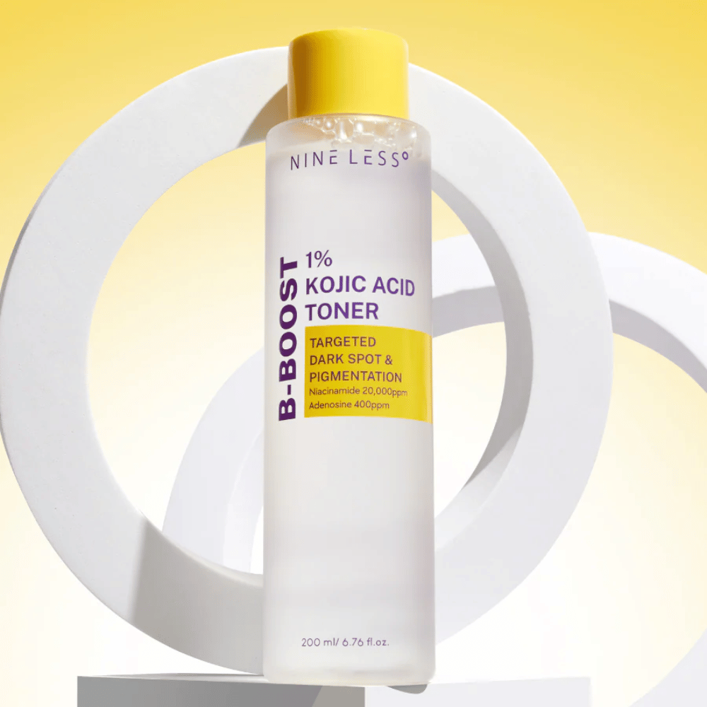 NINE LESS B-Boost 1% Kojic Acid Toner σε κίτρινο φόντο με το κείμενο "Targeted Dark Spot & Pigmentation". Τονωτικό εξομάλυνσης χρωματικού τόνου με νιασιναμίδη και αδενοσίνη.