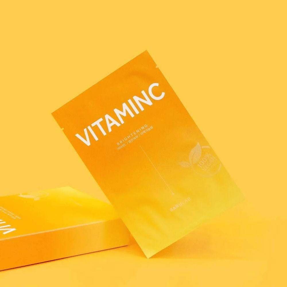 Ένας σωρός από συσκευασίες μασκών "VITAMINC Brightening" BARULAB, όλες με την ένδειξη "100% Vegan Product". Οι συσκευασίες έχουν μια χρωματική απόχρωση σε διάφορες αποχρώσεις του πορτοκαλί και του κίτρινου, τοποθετημένες σε ένα ενιαίο κίτρινο φόντο.