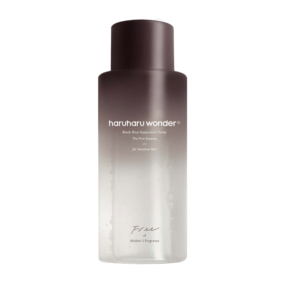 Ένα μπουκάλι haruharu wonder Black Rice Hyaluronic Toner The First Essence, με σκούρα καφέ προς διαφανή διαβάθμιση και το κείμενο "Free of Alcohol & Fragrance", σε λευκό φόντο.
