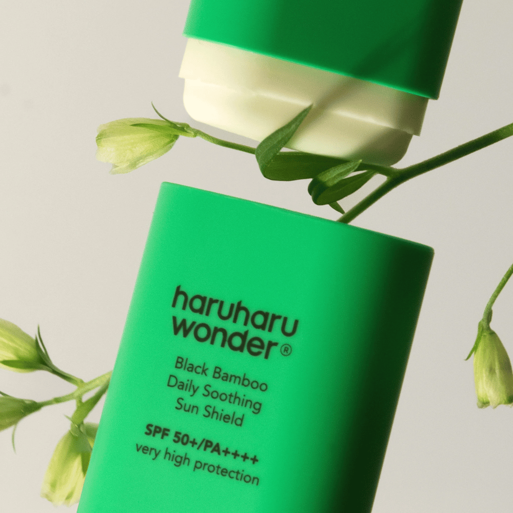 Κοντινό πλάνο του Haruharu Wonder Black Bamboo Daily Soothing Sun Shield – ένα πράσινο αντηλιακό σε μορφή στικ με SPF 50+ PA++++, περιτριγυρισμένο από πράσινες λεπτομέρειες φυτών.