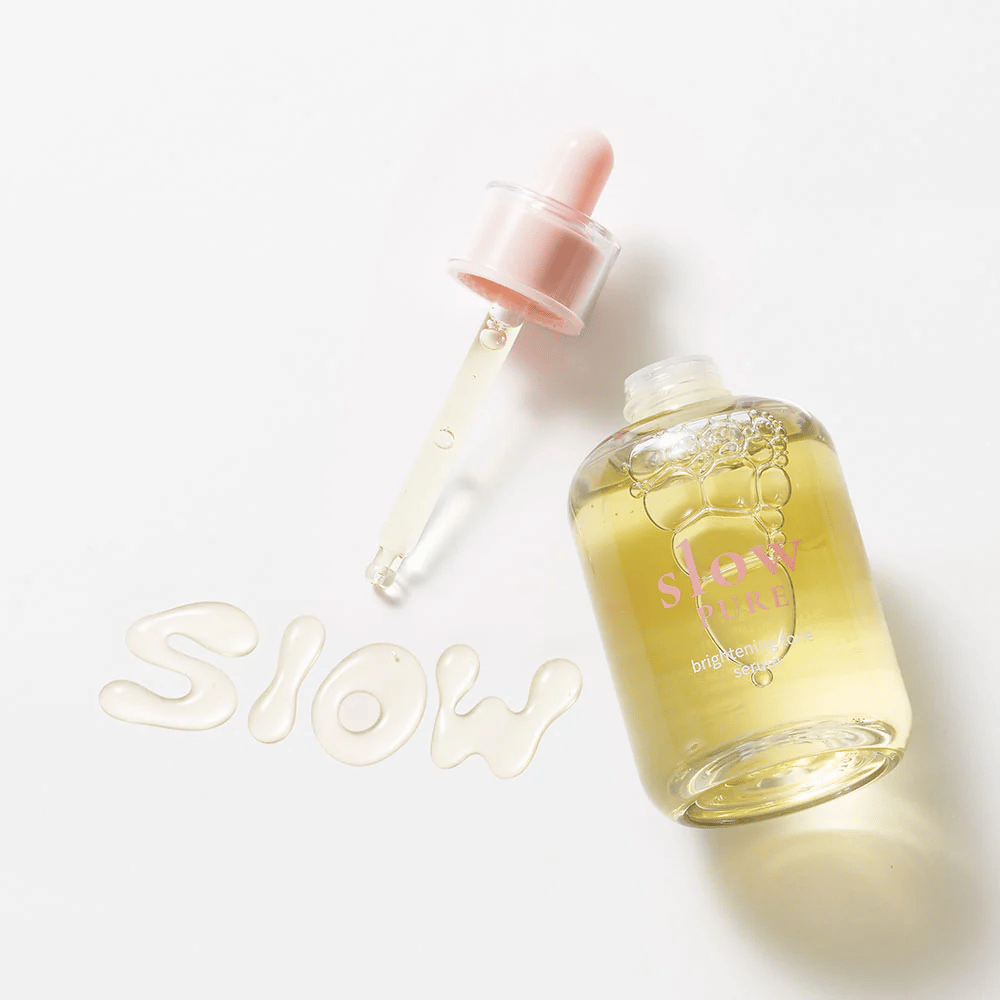 Slow Pure Brightening Tone Serum με ανοιχτή πιπέτα, κείμενο γραμμένο σε ορό στην επιφάνεια: "Slow".