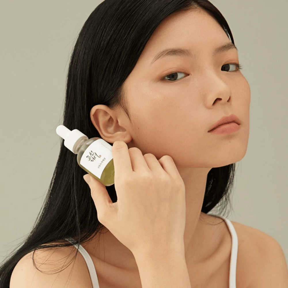 Μοντέλο κρατάει Beauty of Joseon Calming Serum στο μάγουλο – πράσινο τσάι και πανθενόλη που ενισχύουν το δερματικό φραγμό.
