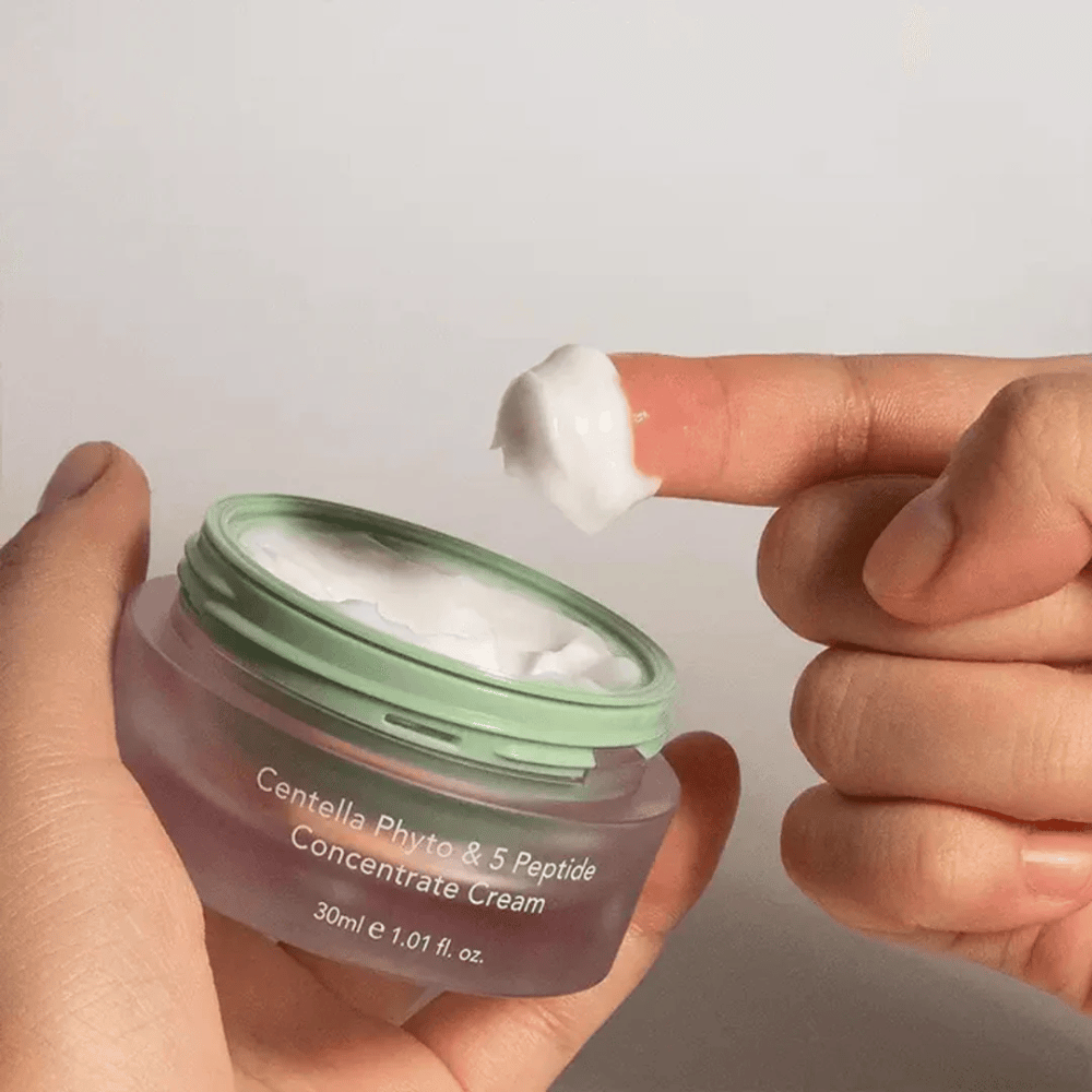Χέρι που παίρνει μια ποσότητα Centella Phyto & 5 Peptide Concentrate Cream από ένα βάζο.