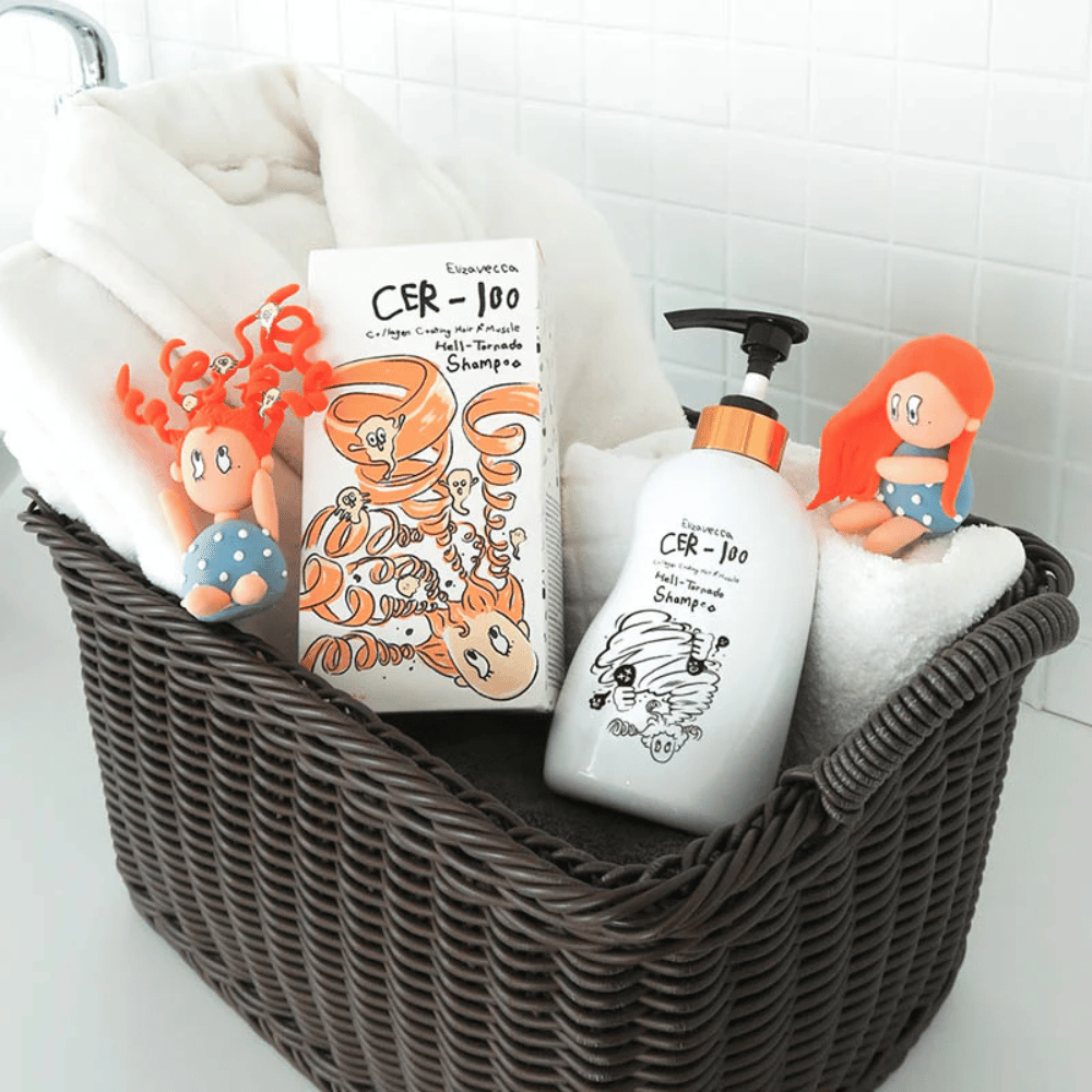 Εικόνα παρουσίασης με το Elizavecca CER-100 Shampoo και τη συσκευασία του τοποθετημένα σε ένα καλάθι μαζί με πετσέτες. Παιχνιδιάρικες φιγούρες από τον σχεδιασμό της συσκευασίας αναδεικνύουν το μοναδικό και δημιουργικό στυλ της μάρκας.