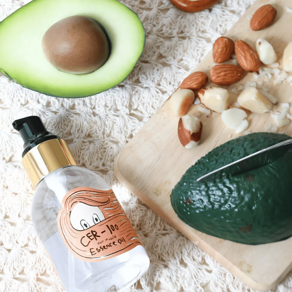 Elizavecca CER-100 Hair Muscle Essence Oil συστατικά – κοντινή λήψη με αβοκάντο και φυτικά έλαια που δείχνει ένα θρεπτικό λάδι μαλλιών που βοηθά στο να μαλακώσει και να περιποιηθεί τα μαλλιά.