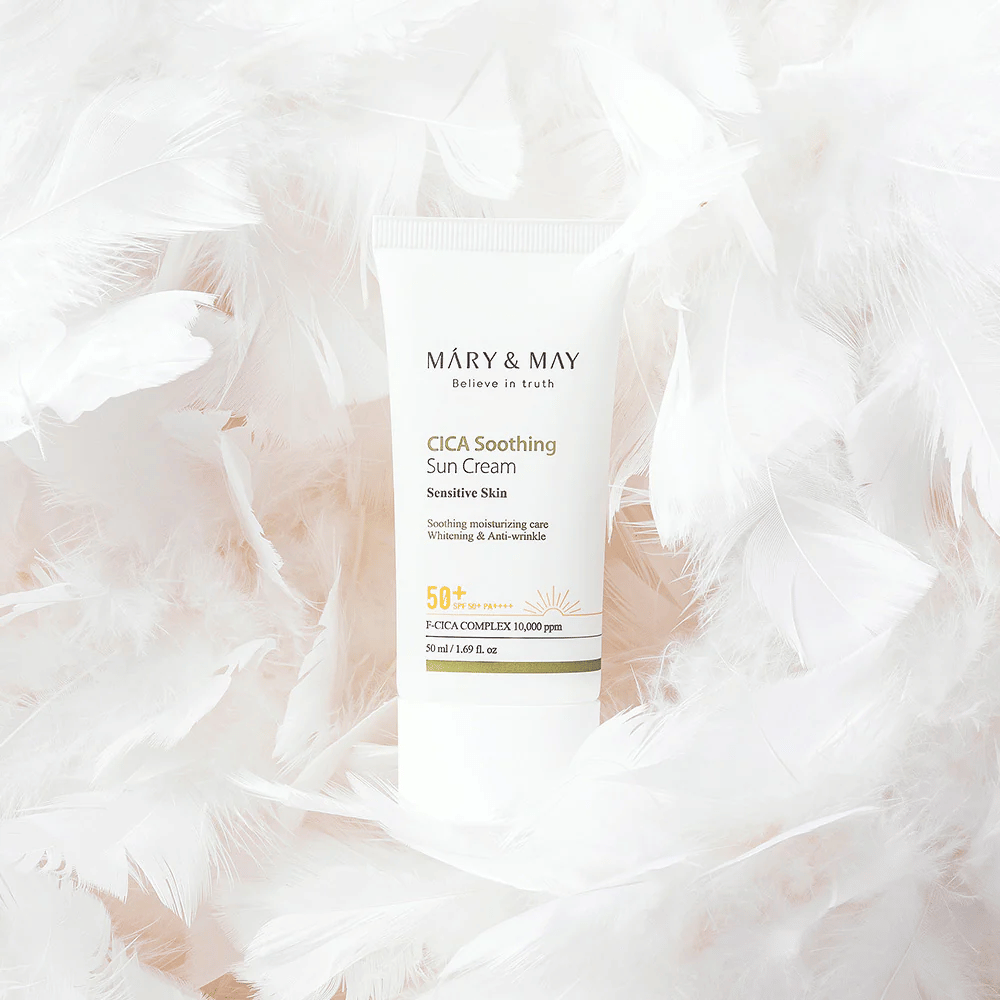 Το Mary&May CICA Soothing Sun Cream περιβαλλόμενο από απαλά λευκά φτερά. Η εικόνα αποπνέει αίσθηση απαλότητας, άνεσης και ελαφριάς σύνθεσης, κατάλληλης για ευαίσθητο δέρμα.