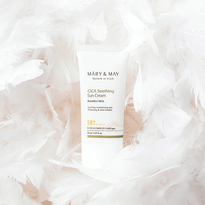 Το Mary&May CICA Soothing Sun Cream περιβαλλόμενο από απαλά λευκά φτερά. Η εικόνα αποπνέει αίσθηση απαλότητας, άνεσης και ελαφριάς σύνθεσης, κατάλληλης για ευαίσθητο δέρμα.
