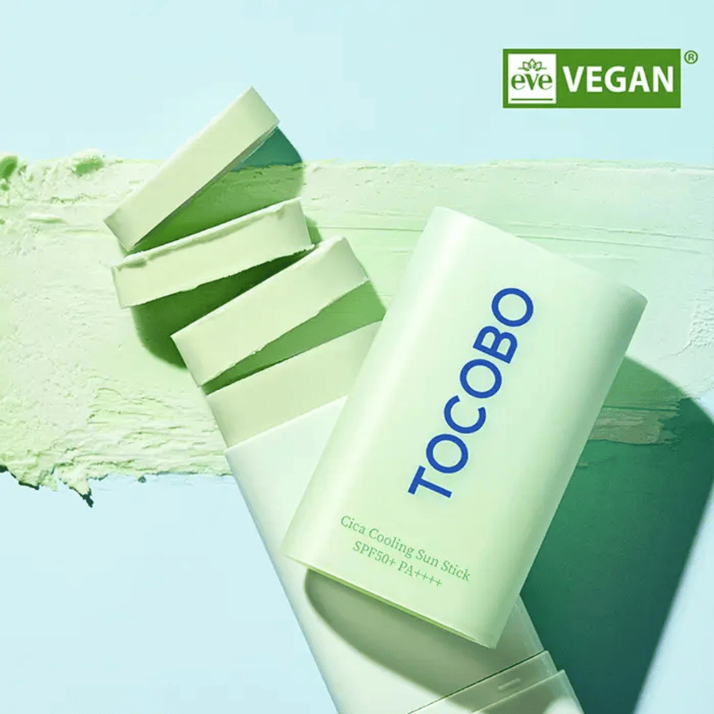 Tocobo Cica Cooling Sun Stick SPF50+ PA++++ σε ανοιχτό πράσινο συσκευασία με σήμανση vegan (EVE VEGAN), που βρίσκεται πάνω σε στρώμα πράσινου αντηλιακού στικ.