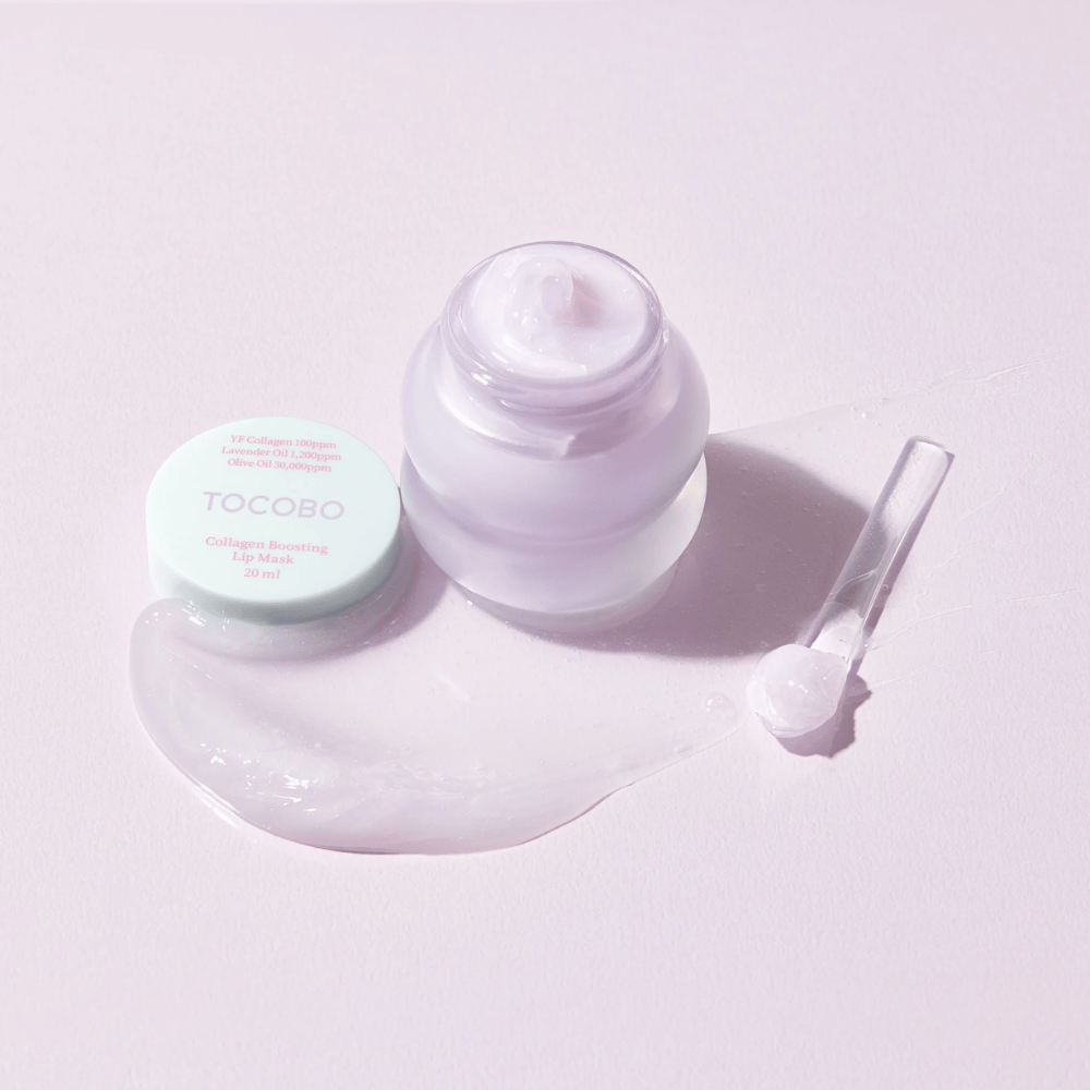 Ανοιχτό βάζο TOCOBO Collagen Boosting Lip Mask με σπάτουλα και απλωμένη μωβ κρέμα σε ανοιχτό μωβ φόντο.