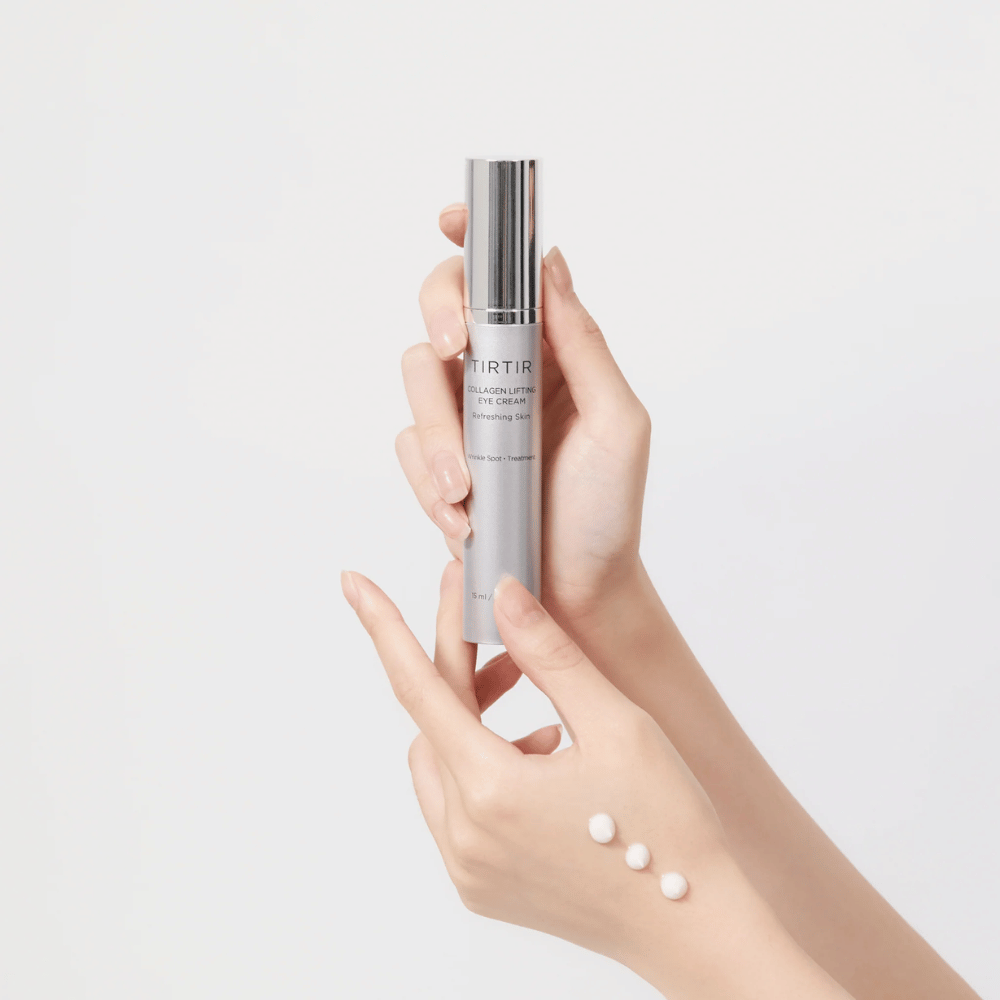 Χέρια που κρατούν ένα σωληνάριο με TIRTIR Collagen Lifting Eye Cream, με προϊόν συμπιεσμένο στο πίσω μέρος του χεριού.