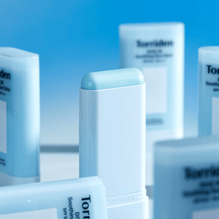 Κοντινό πλάνο του Torriden DIVE IN Soothing Sun Stick που δείχνει την απαλή φόρμουλα αντηλιακού σε μορφή στικ με πολλά προϊόντα στο φόντο.