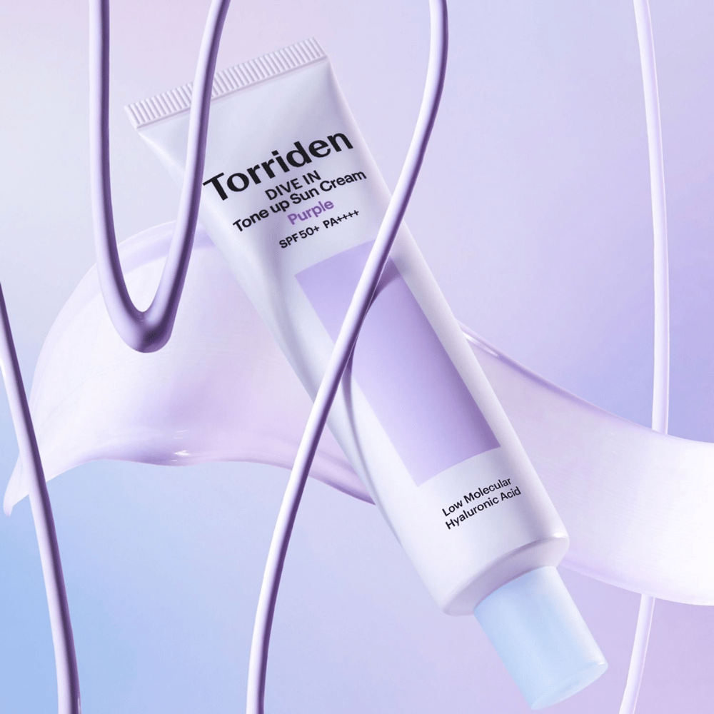 Torriden DIVE IN Tone Up Sun Cream Purple SPF50+ PA++++ παρουσιασμένο σε δημιουργικό σκηνικό προϊόντος με μωβ λεπτομέρειες που αναδεικνύουν την ενυδατική φόρμουλα.