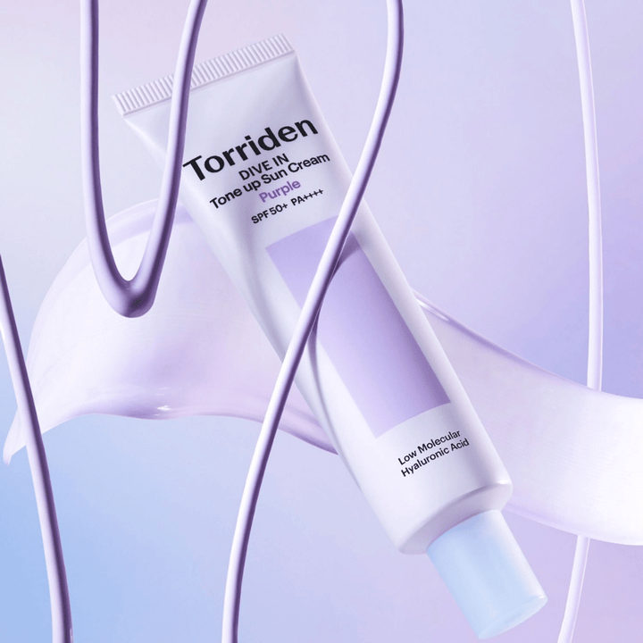 Torriden DIVE IN Tone Up Sun Cream Purple SPF50+ PA++++ παρουσιασμένο σε δημιουργικό σκηνικό προϊόντος με μωβ λεπτομέρειες που αναδεικνύουν την ενυδατική φόρμουλα.
