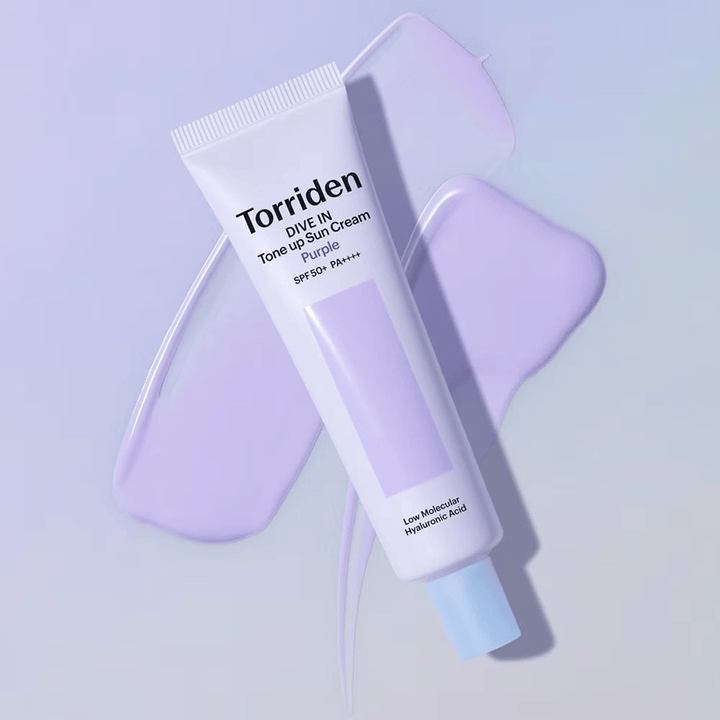 Torriden DIVE IN Tone Up Sun Cream Purple τοποθετημένο πάνω σε απλωμένη μωβ κρέμα που τονίζει την εξομαλυντική για τον τόνο και χαρίζουσα λάμψη δράση.