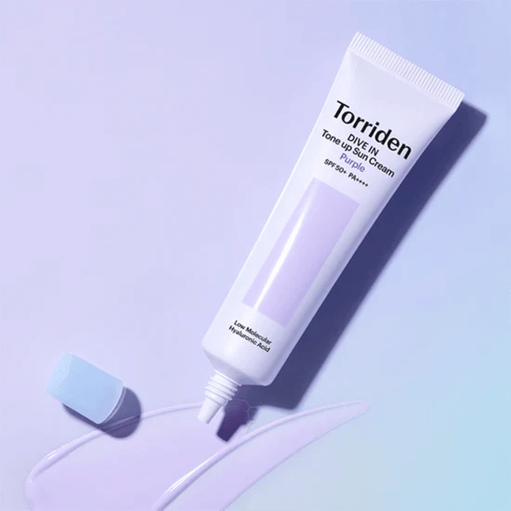 Ανοιχτό σωληνάριο του Torriden DIVE IN Tone Up Sun Cream Purple με μωβ χρωματισμένη υφή αντηλιακής κρέμας που δείχνει τη διορθωτική ως προς το χρώμα φόρμουλα του προϊόντος.
