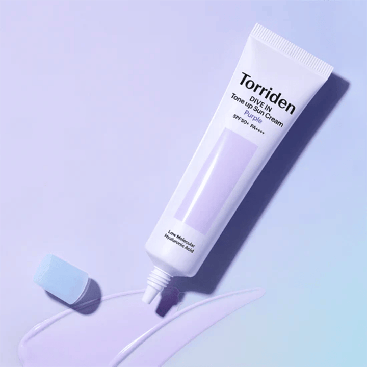 Ανοιχτό σωληνάριο του Torriden DIVE IN Tone Up Sun Cream Purple με μωβ χρωματισμένη υφή αντηλιακής κρέμας που δείχνει τη διορθωτική ως προς το χρώμα φόρμουλα του προϊόντος.