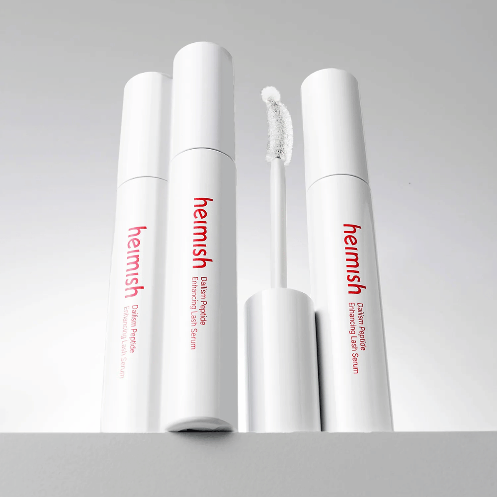 Πολλές συσκευασίες του Heimish Dailism Peptide Enhancing Lash Serum εμφανίζονται μαζί με το κυρτό βουρτσάκι απλικατέρ. Η εικόνα αναδεικνύει τον κομψό σχεδιασμό του προϊόντος και το βουρτσάκι ακριβείας για εύκολη εφαρμογή.