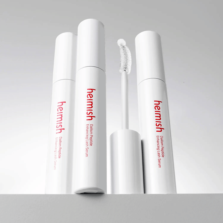 Πολλές συσκευασίες του Heimish Dailism Peptide Enhancing Lash Serum εμφανίζονται μαζί με το κυρτό βουρτσάκι απλικατέρ. Η εικόνα αναδεικνύει τον κομψό σχεδιασμό του προϊόντος και το βουρτσάκι ακριβείας για εύκολη εφαρμογή.
