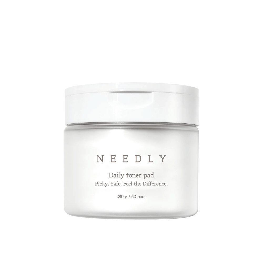 Ένα λευκό βάζο με Needly Daily Toner Pad. Η συσκευασία έχει μινιμαλιστικό κείμενο που περιγράφει το προϊόν και περιέχει 280 g, που αντιστοιχεί σε 60 τονέρ παντς. Το κείμενο γράφει 'Picky. Safe. Feel the Difference.