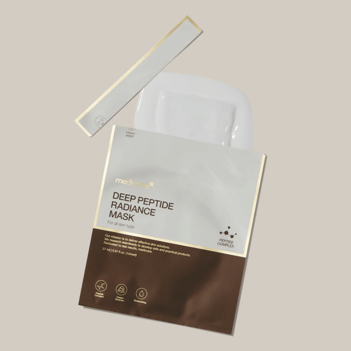 Medicube Deep Peptide Radiance Mask σε ανοιγμένη συσκευασία με ορατή μάσκα φύλλου, υγρή παρουσίαση σε ουδέτερο φόντο.