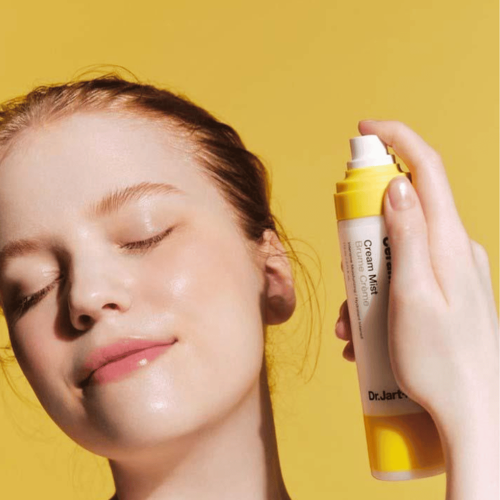 Μια γυναίκα κρατάει ένα μπουκάλι Dr. Jart+ Ceramidin Cream Mist 110ml στο πρόσωπό της, προωθώντας τα οφέλη ενυδάτωσης και τη βίγκαν σύνθεση του.