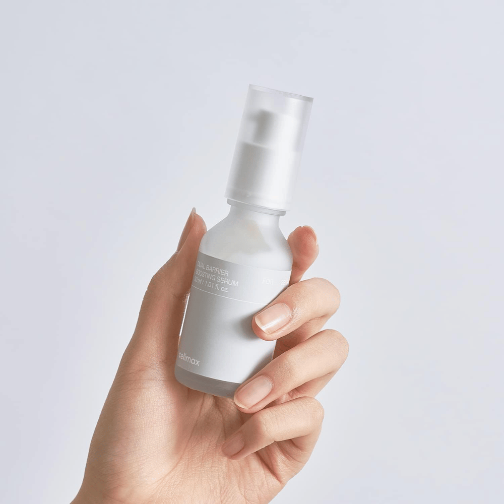 Celimax Dual Barrier Boosting Serum στο χέρι, μινιμαλιστική συσκευασία που δείχνει κορεάτικο ορό ενίσχυσης φραγμού για ευαίσθητο δέρμα.