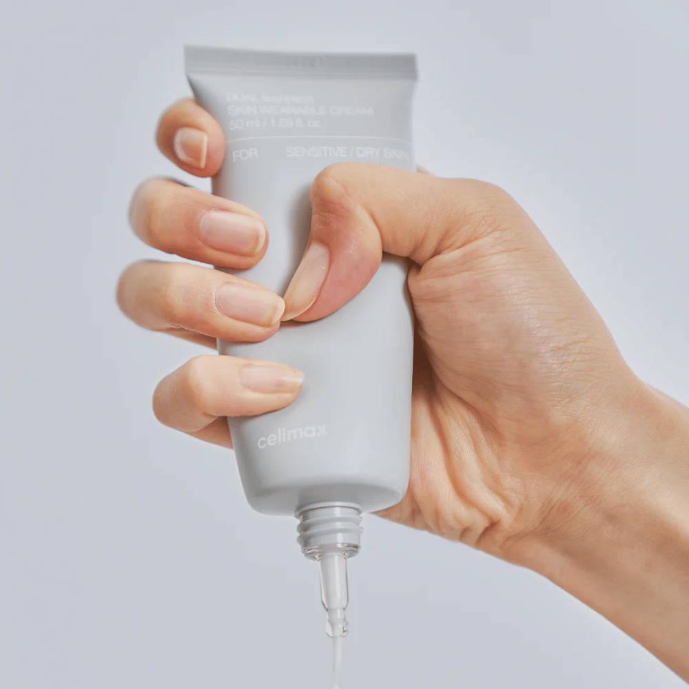 Χέρι που εφαρμόζει Celimax Dual Barrier Skin Wearable Cream, κρέμα προσώπου που ενισχύει το φραγμό για ευαίσθητο και ξηρό δέρμα που παρέχει μακροχρόνια ενυδάτωση και προστατεύει το φραγμό του δέρματος.