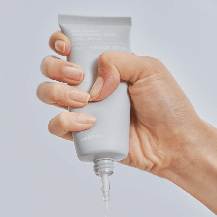 Χέρι που εφαρμόζει Celimax Dual Barrier Skin Wearable Cream, κρέμα προσώπου που ενισχύει το φραγμό για ευαίσθητο και ξηρό δέρμα που παρέχει μακροχρόνια ενυδάτωση και προστατεύει το φραγμό του δέρματος.