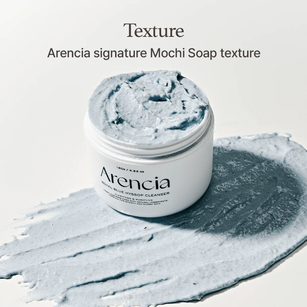 Ανοιχτό βάζο με Arencia Fresh Blue Hyssop Rice Mochi Cleanser, τοποθετημένο πάνω σε ένα απλωμένο στρώμα της μπλε, κρεμώδους φόρμουλας καθαρισμού που δείχνει την υφή του που μοιάζει με μοτσί.