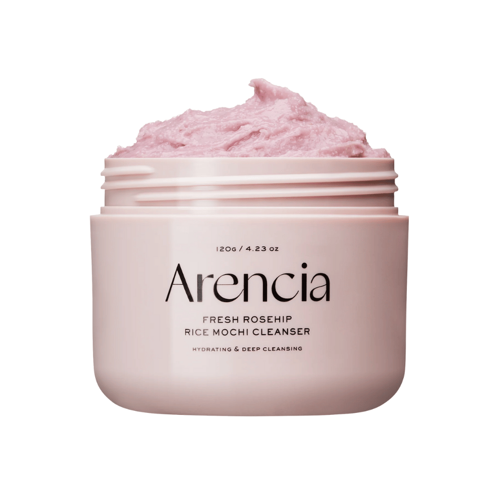Κοντινή λήψη ενός ροζ βάζου με Arencia Royal Rosehip Cleanser, γεμάτο με ροζ κρέμα καθαρισμού με υφή σαν χτυπημένη, μοτσί. Το κείμενο στο βάζο δείχνει ότι το προϊόν ενυδατώνει και καθαρίζει σε βάθος.