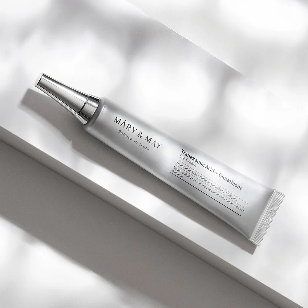 Κοντινό πλάνο της Mary&May Tranexamic Acid + Glutathione Eye Cream με μεταλλικό απλικατέρ, σχεδιασμένο για να φωτίζει τους μαύρους κύκλους και να εξομαλύνει τον τόνο της επιδερμίδας γύρω από τα μάτια.