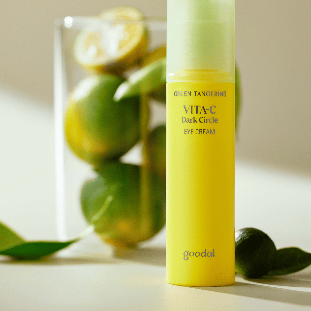 Ένα μπουκάλι Goodal Green Tangerine Vita C Dark Circle Eye Cream 30ml σε ένα τραπέζι δίπλα σε ένα λάιμ.
