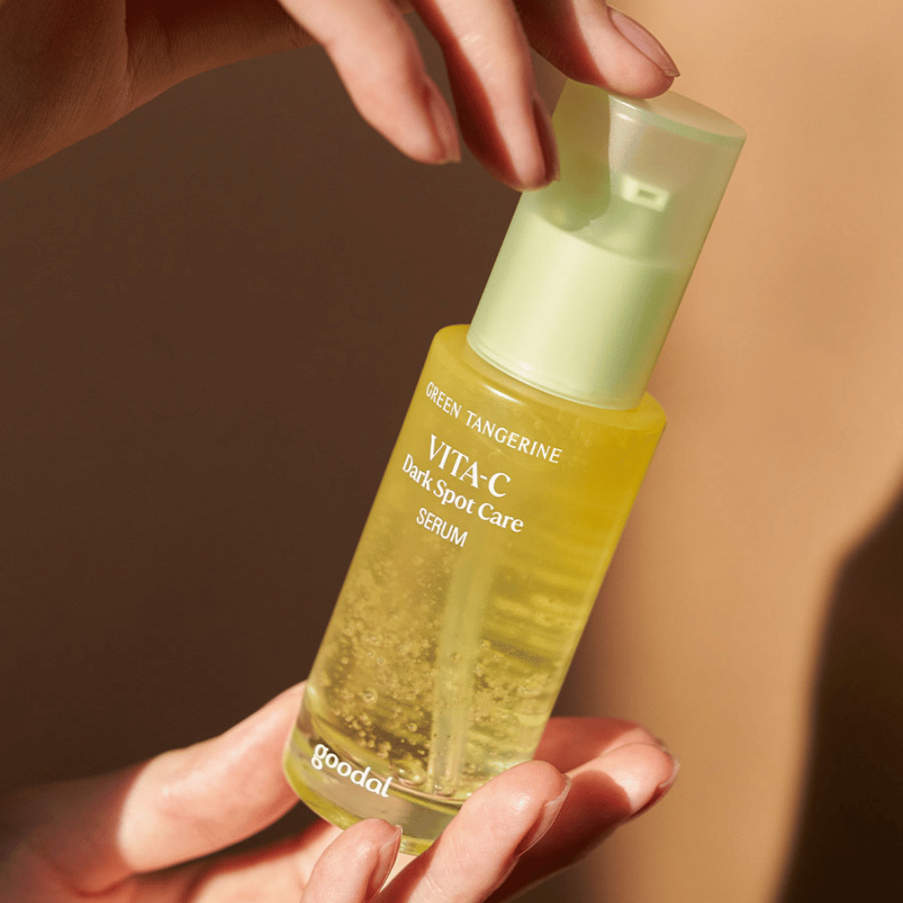 Ένα άτομο που κρατάει ένα μπουκάλι Green Tangerine Vita C Dark Spot Care Serum 40ml από Goodal για υπερμελάγχρωση και φροντίδα σκούρων κηλίδων.