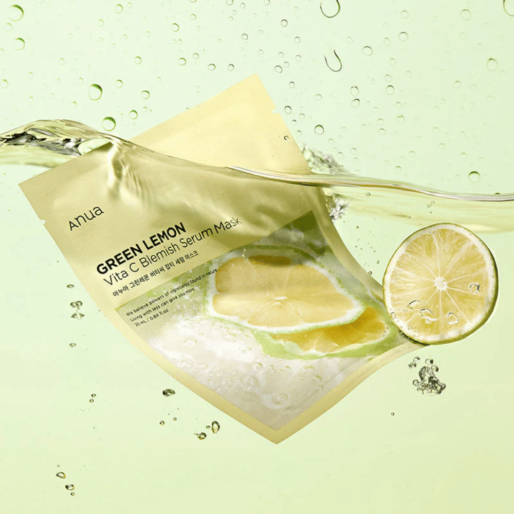 Μια ζωντανή εικόνα της συσκευασίας Anua Green Lemon Vita C Blemish Serum Mask με διάφανες σταγόνες νερού και φέτες πράσινου λεμονιού γύρω-γύρω. Η συσκευασία είναι εν μέρει καλυμμένη από ένα ρεύμα νερού σε ένα ανοιχτό πράσινο φόντο.