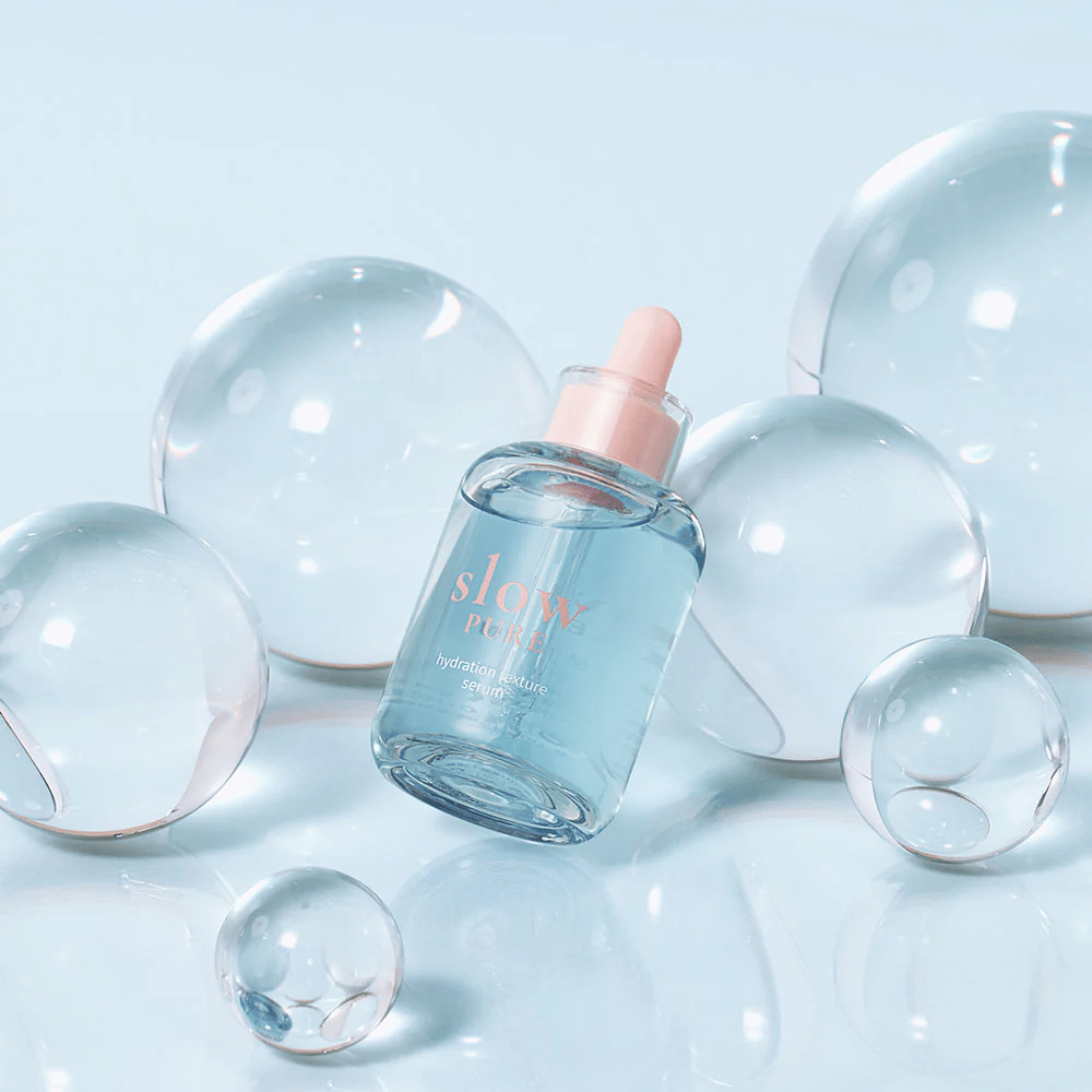 Slow Pure Hydration Texture Serum τοποθετημένο ανάμεσα σε διαφανείς φυσαλίδες, σύμβολο για έντονη ενυδάτωση.