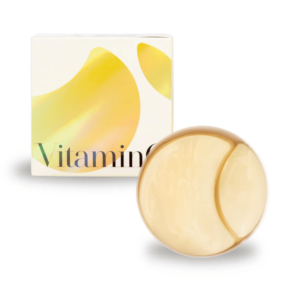 K-Secret Extra Illuminating Eye Gel Patches με βιταμίνη C σε χρυσογυαλιστερό υδρογέλη, βάζο και συσκευασία στο φόντο.