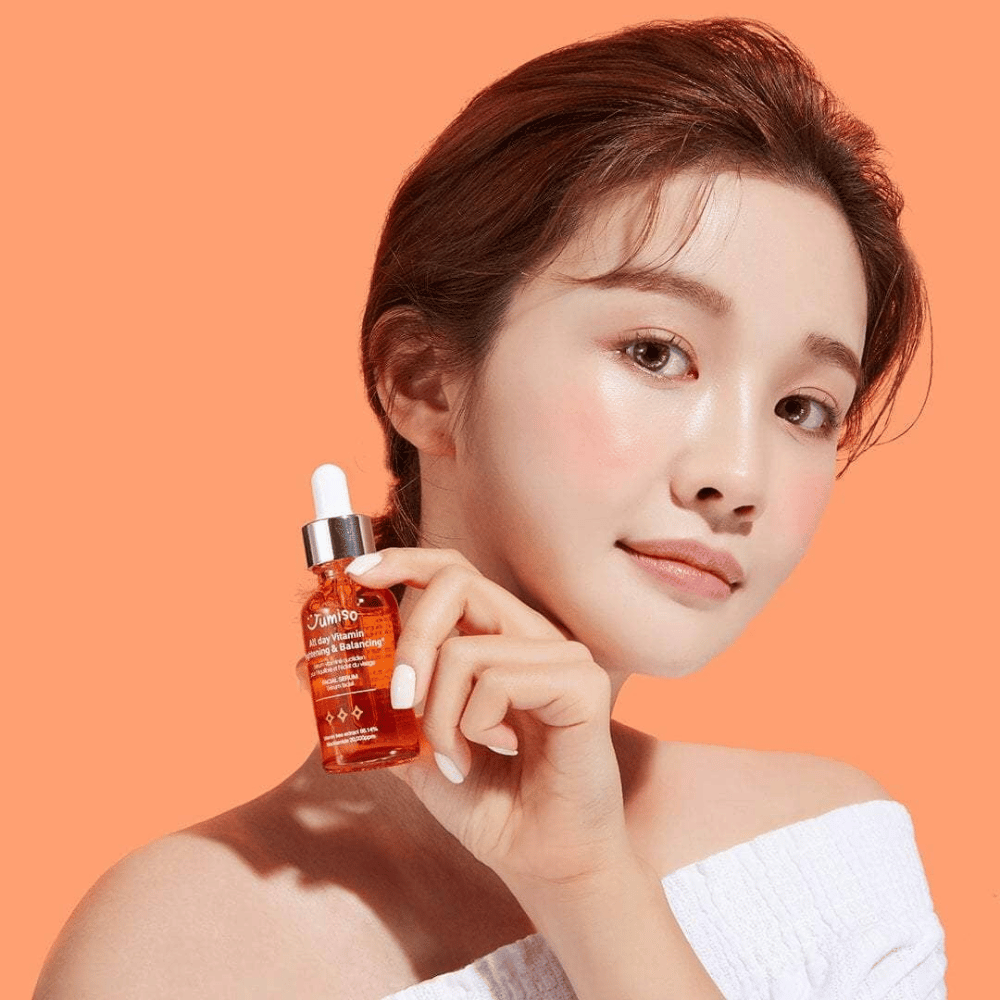 Μια γυναίκα που κρατάει ένα μπουκάλι JUMISO All Day Vitamin Brightening & Balancing Facial Serum 30ml.