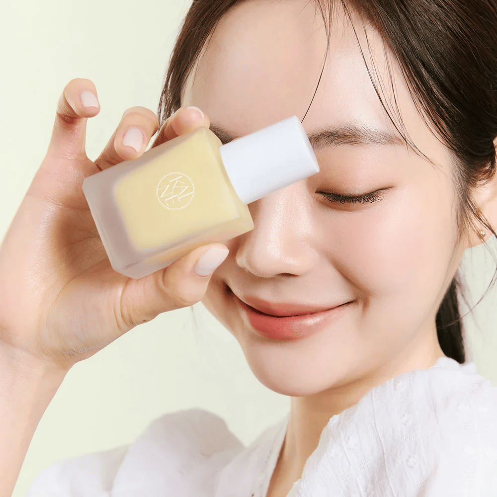 Μια γυναίκα κρατά ένα μπουκάλι KAINE Vita Drop Serum 30ml.