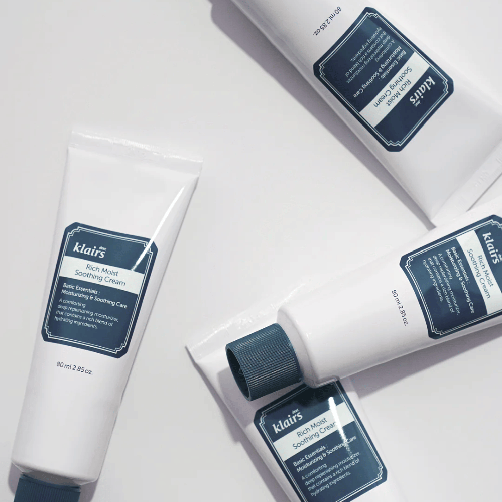 Πολλοί σωλήνες από Klairs Rich Moist Soothing Cream στρατηγικά τοποθετημένοι σε μια φωτεινή επιφάνεια, με σκιές που δημιουργούν βάθος.