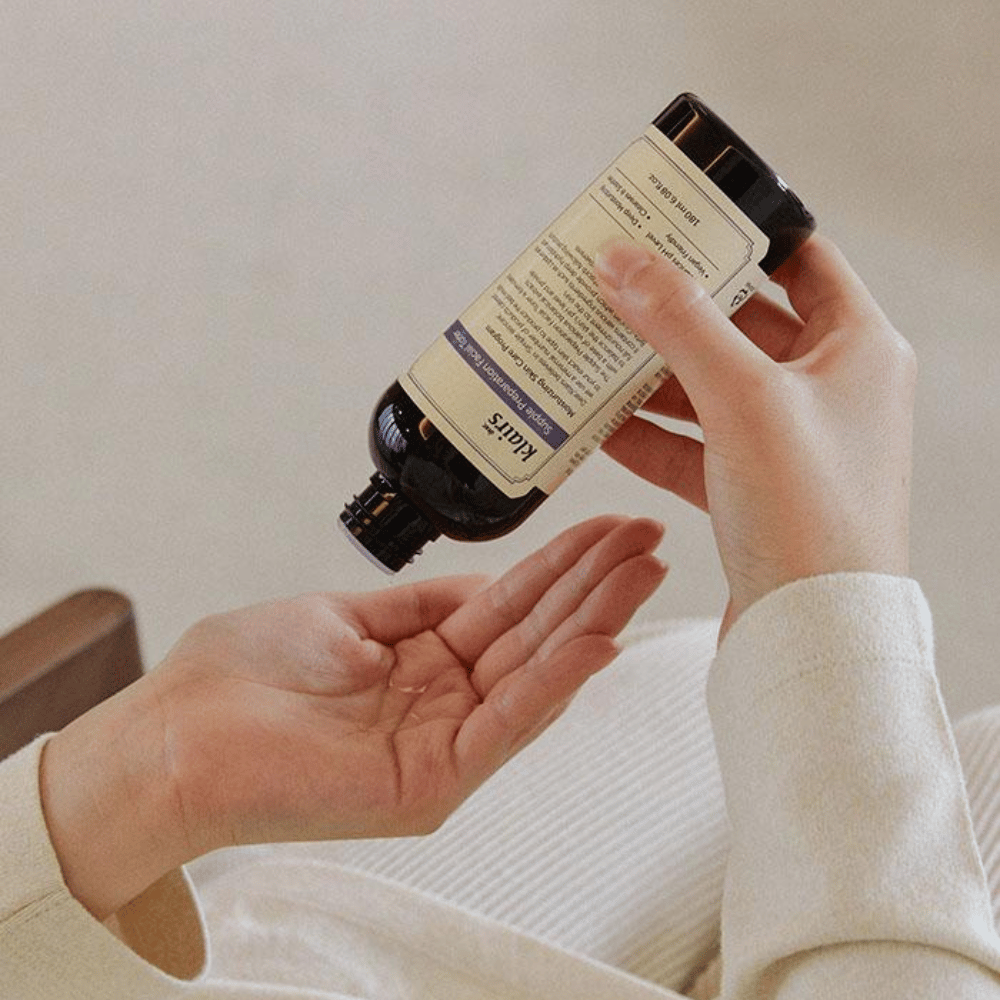 Ένα άτομο κρατάει ένα μπουκάλι του Klairs Supple Preparation Facial Toner ανάποδα πάνω από το χέρι του, έτοιμο να δοσολογήσει το προϊόν.