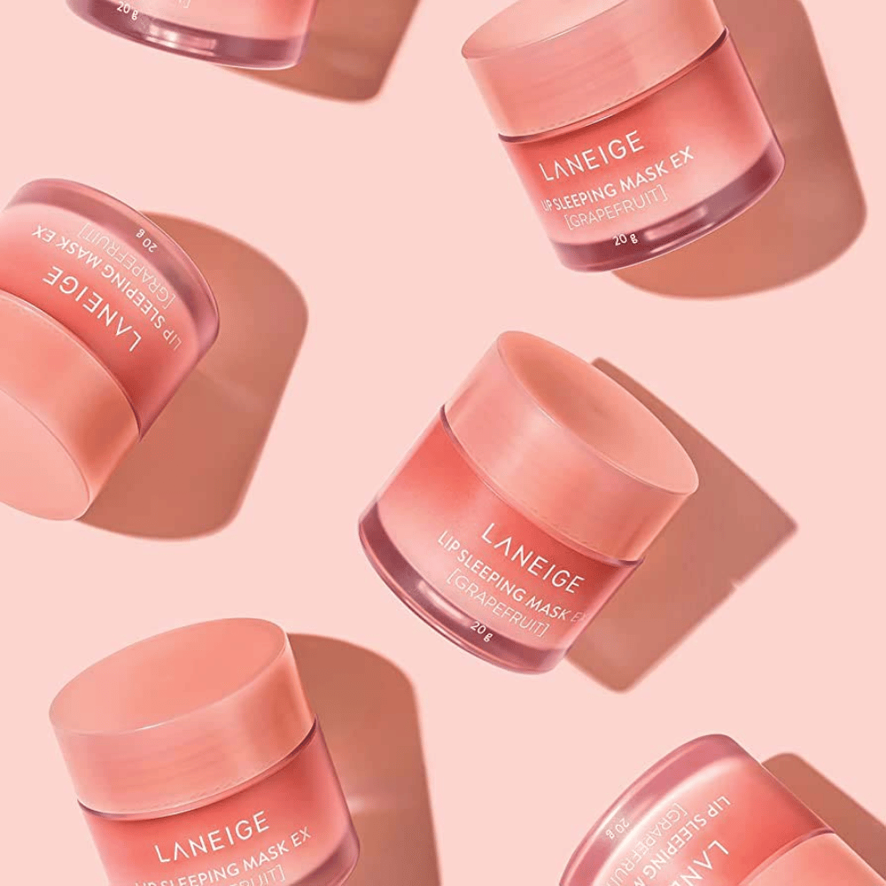 Τέσσερα βάζα LANEIGE Lip Sleeping Mask Γκρέιπφρουτ 20g σε ροζ φόντο, προωθεί το γκρέιπφρουτ και την ενυδάτωση.