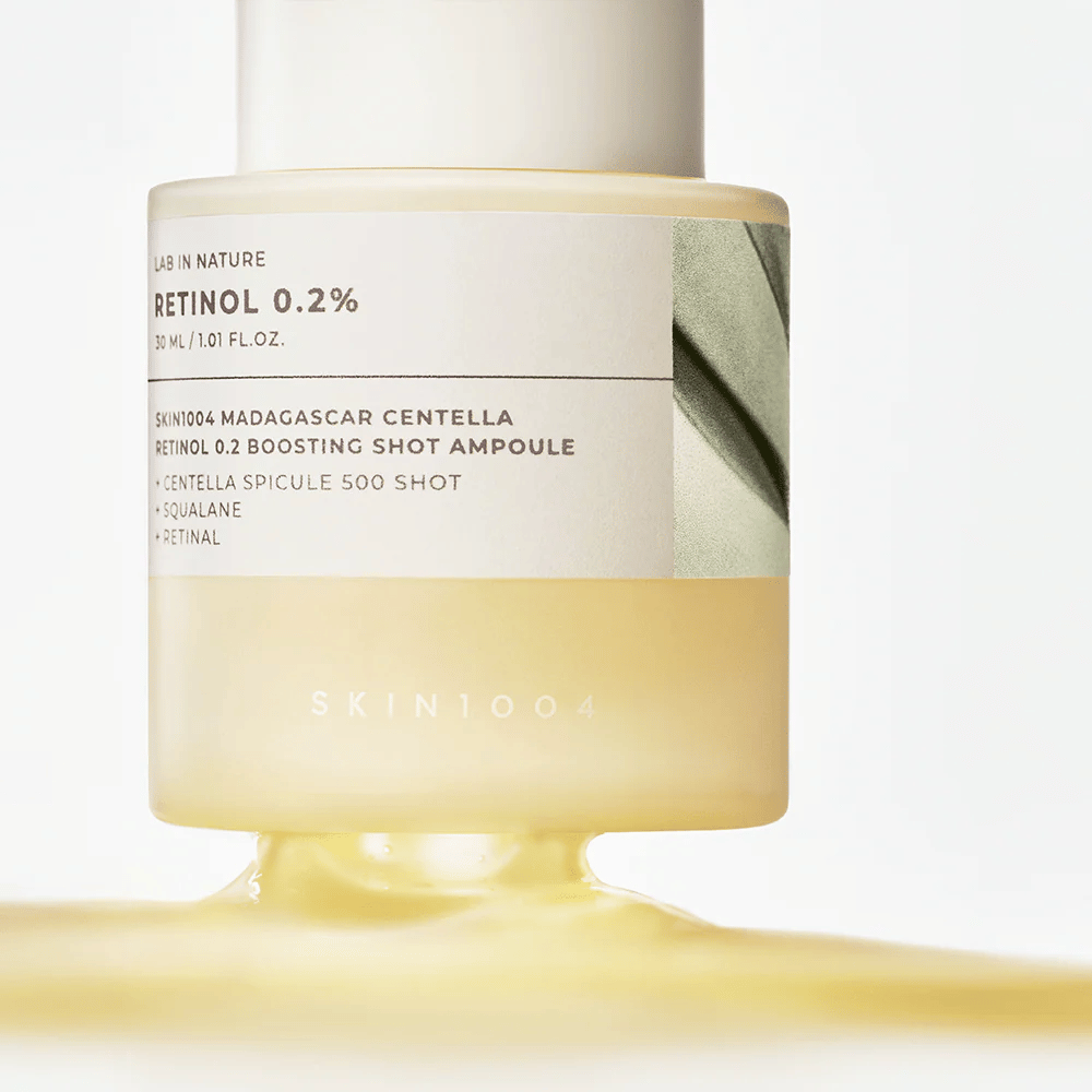 Κοντινή εικόνα του SKIN1004 Madagascar Centella Retinol 0.2 Boosting Shot Ampoule που δείχνει την ελαφρώς κίτρινη, μεταξένια υφή του ορού ρετινόλης για νυχτερινή ανανέωση του δέρματος.