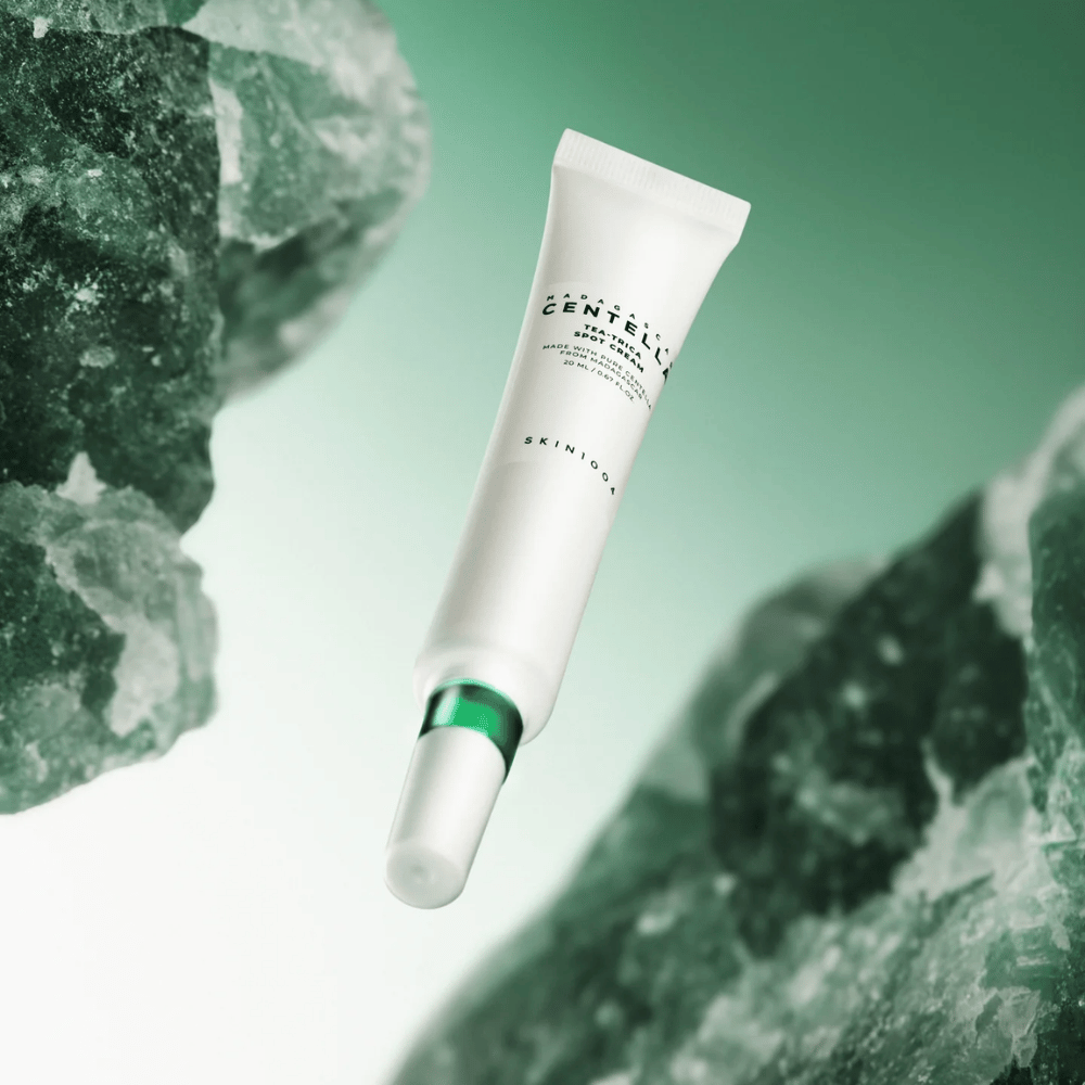 SKIN1004 Madagascar Centella Tea-Trica Spot Cream 20 ml κατά της ακμής και των σπυριών, εικόνα προϊόντος με πράσινο φόντο και κρυσταλλική δομή – καταπραϋντική θεραπεία σημείου με centella asiatica και tea tree.