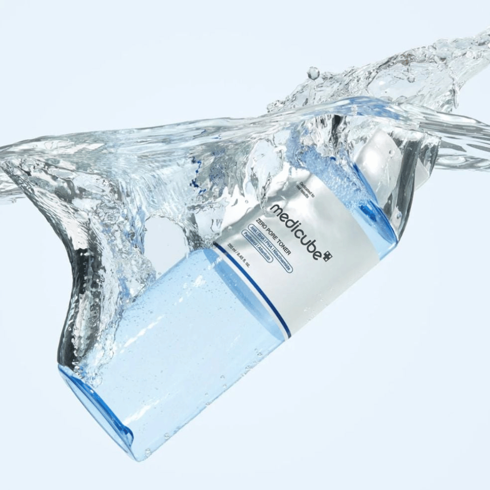 Medicube Zero Pore Toner 250 ml, απολεπιστικό τόνερ με AHA, BHA και PHA. Διαφανές μπλε μπουκάλι που περιβάλλεται από μια μεγάλη πιτσιλιά νερού.
