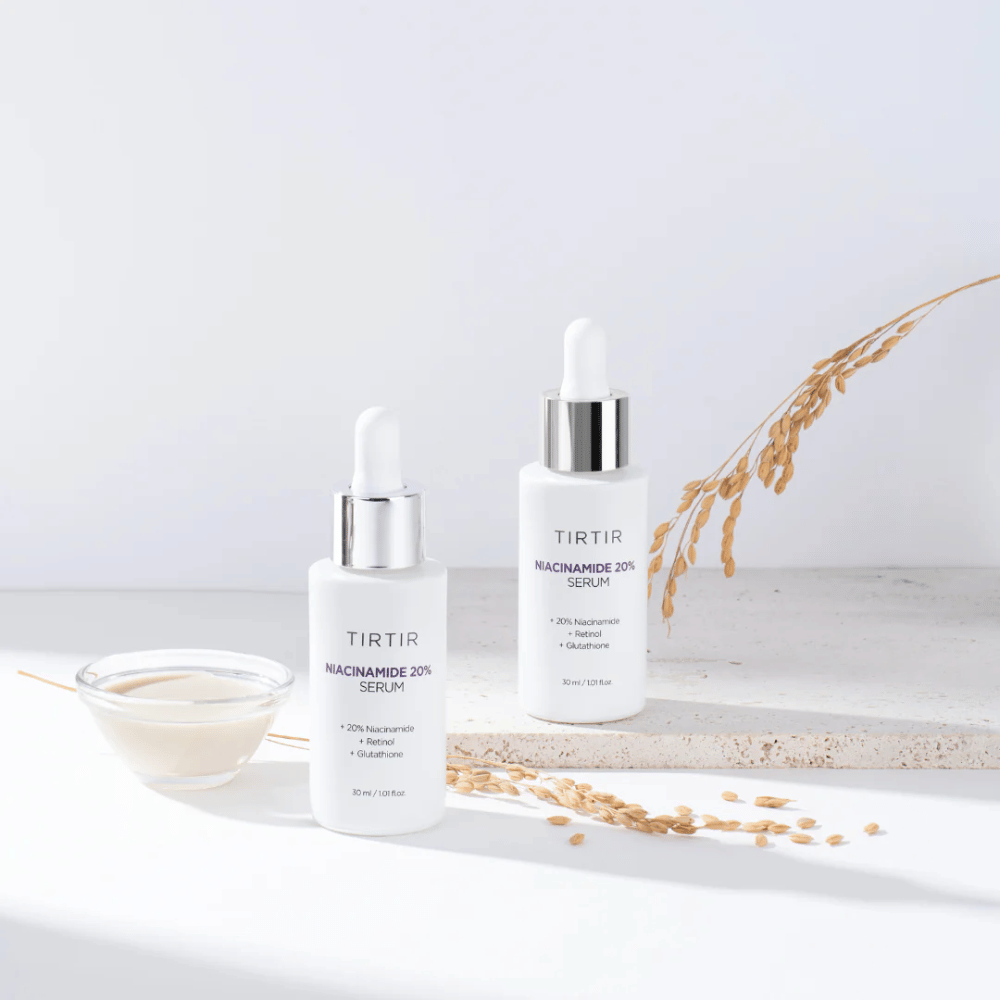 Δύο μπουκάλια του Tirtirs "Niacinamide 20% Serum" εμφανίζονται σε φωτεινή επιφάνεια μαζί με ένα μικρό μπολ με κρεμώδη ουσία και μερικά στελέχη ξηρών φυτών. Ο ορός περιέχει 20% νιασιναμίδη, ρετινόλη και γλουταθειόνη, που συμβάλλει στη βελτίωση της εμφάνισης και της υφής του δέρματος.