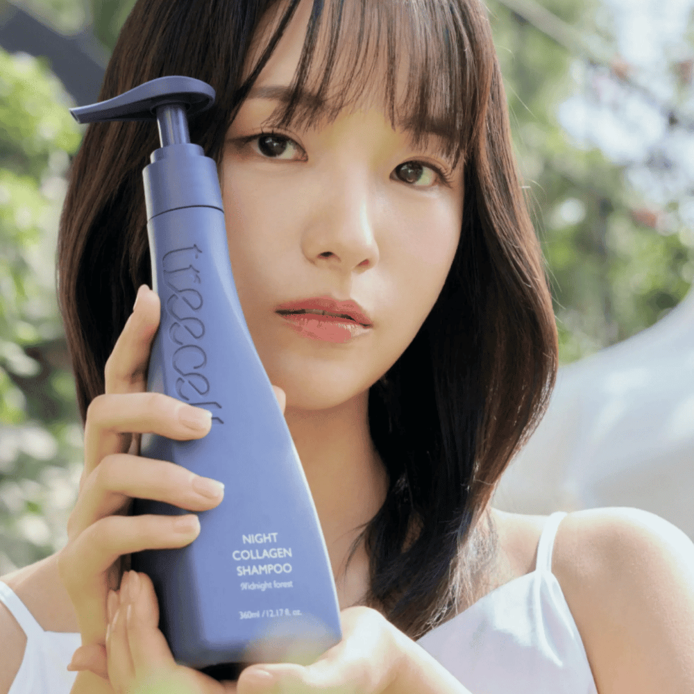 Γυναίκα κρατά το Treecell Night Collagen Shampoo Midnight Forest σε φυσικό περιβάλλον. Η εικόνα αποπνέει υγιή μαλλιά, λάμψη και premium αίσθηση με έμφαση στη φροντίδα των μαλλιών και του τριχωτού της κεφαλής.